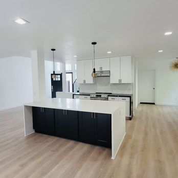 Cordada Construction Inc - A clean and open kitchen design featuring a large waterfall island with black lower cabinets, white shaker cabinetry, quartz countertops. - General Contractors Near Me Cordada Construction Inc - A clean and open kitchen design featuring a large waterfall island with black lower cabinets, white shaker cabinetry, quartz countertops. - General Contractors Near Me