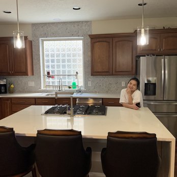 Apex Builders - a woman sitting at a kitchen island - General Contractors Near Me