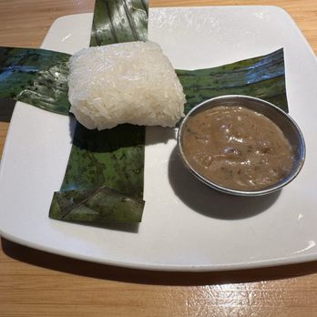Malai Kitchen - Sticky rice wrapped in a banana leaf (don't eat it) and side dipping sauce. I unwrapped mine so you could see it. - Thai Near Me - Fort Worth, Texas Malai Kitchen - Sticky rice wrapped in a banana leaf (don't eat it) and side dipping sauce. I unwrapped mine so you could see it. - Thai Near Me - Fort Worth, Texas