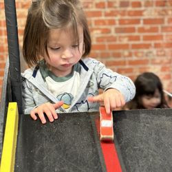 Southern California Children's Museum - SCCM - Toddler boy demonstrating gravity with toy car off slope