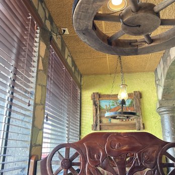 Mi Mexico - a wooden bench with a wheel hanging from the ceiling - Mexican Near Me - Montrose, Colorado