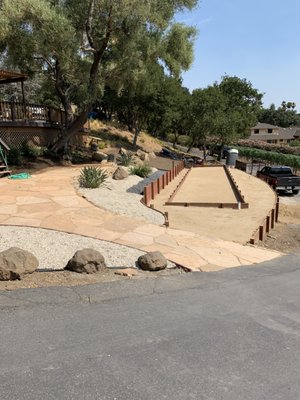 Flagstone patio with Bocce Court - Construction of two retaining walls, leveling of ground with base rock and compacted, to be able to build a 60 ft. Bocce court, additionally the patio was made with flagstone and we added decoration with plants and decorative gravel.