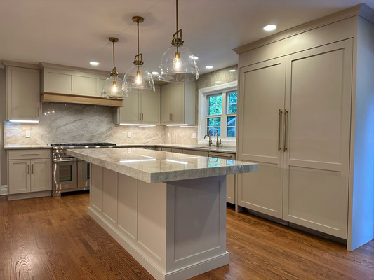 Timeless Elegance in Millburn, NJ: A Kitchen Remodel That Shines - We transformed this Millburn kitchen into a stunning, light-filled space! The design features beautiful greige shaker cabinetry perfectly complemented by luxurious veined natural stone countertops and full-height backsplash. We accented the space with warm brass hardware and lighting, including eye-catching glass dome pendants over the oversized island. The custom wood hood vent and high-end stainless steel appliances complete this chef's dream. Ready for a kitchen that blends classic style with modern amenities? Timeless Elegance in Millburn, NJ: A Kitchen Remodel That Shines - We transformed this Millburn kitchen into a stunning, light-filled space! The design features beautiful greige shaker cabinetry perfectly complemented by luxurious veined natural stone countertops and full-height backsplash. We accented the space with warm brass hardware and lighting, including eye-catching glass dome pendants over the oversized island. The custom wood hood vent and high-end stainless steel appliances complete this chef's dream. Ready for a kitchen that blends classic style with modern amenities?