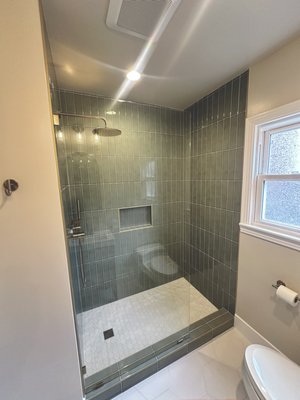 Bathroom Remodel East Sacramento - This custom bathroom remodel transformed an outdated bathroom with a tub-to-shower conversion, creating a more spacious and functional layout. The project included a new waterproof shower system, custom vertical tile, a built-in shower niche, frameless glass enclosure, brushed gold plumbing fixtures, and a custom hexagon tile shower pan. Additional upgrades included a modern wood vanity, decorative lighting, large-format hexagon tile flooring, fresh wall texture, new paint, and premium finish work throughout. Every detail was completed with quality craftsmanship, durable materials, and attention to detail to create a beautiful bathroom built to last.