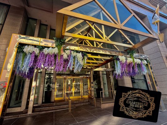 Hotel Entrance Faux Floral Installation - Chartreuse by Roje is proud to unveil a stunning new floral installation gracing the O'Farrell Street entrance of Hotel Nikko San Francisco. This vibrant display features a cascade of silk wisteria and florals in shades of lavender, ivory, and soft blue, luxuriously draped across the gold-trimmed entryway. Each element is expertly crafted from high-quality outdoor-grade silk, ensuring year-round beauty with zero maintenance.

Specifically designed to enhance the hotel’s sophisticated facade, this installation brings a bold touch of elegance and color to downtown San Francisco. As always, our work blends durability with drama—an invitation to experience floral design in a new, lasting way.