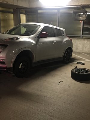 Flat tire removal and spare replacement - This particular vehicle was in a small garage parking with a inclined pavement so the customer was unable to lift the car without the jack falling over and damaging the vehicle.