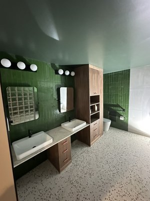 Bold Modern Bathroom Remodel - Bold Modern Bathroom Remodel – Seattle, WA
By DM Construction Group
This unique and modern bathroom remodel in Seattle showcases a bold fusion of natural materials, vivid color, and thoughtful accessibility features. Designed with both style and function in mind, this space reflects a refined take on contemporary living.
Key Features:
• Vibrant Green Accent Tile Walls:
Full-height vertical green tile walls add striking personality and depth to the space, creating a rich contrast with the warm wood cabinetry and terrazzo flooring.
• Custom Floating Double Vanity:
A fully custom-built vanity with open shelving, soft-close drawers, and sleek integrated countertops offers ample storage while maintaining an airy, open feel. Dual vessel sinks and matte black faucets complete the modern look.
• Accessible Shower Space:
The walk-in, barrier-free shower features grab bars, a bench area, a rain-style ceiling-mounted shower head, and a handheld fixture. This design balances luxury with practical functionality.
• Concrete Freestanding Soaking Tub:
A sculptural deep soaking tub sits against the accent wall, framed by clean white tile and a frosted privacy window, offering a spa-like experience.
• Modern Lighting & Finishes:
Globe-style vanity lights, matte black fixtures, and built-in niches complete the high-end, modern aesthetic.
From layout to finish, this bathroom remodel reflects DM Construction Group’s dedication to craftsmanship, creativity, and client comfort. Whether you’re updating for accessibility, luxury, or both—we’re here to help bring your vision to life. Bold Modern Bathroom Remodel - Bold Modern Bathroom Remodel – Seattle, WA
By DM Construction Group
This unique and modern bathroom remodel in Seattle showcases a bold fusion of natural materials, vivid color, and thoughtful accessibility features. Designed with both style and function in mind, this space reflects a refined take on contemporary living.
Key Features:
• Vibrant Green Accent Tile Walls:
Full-height vertical green tile walls add striking personality and depth to the space, creating a rich contrast with the warm wood cabinetry and terrazzo flooring.
• Custom Floating Double Vanity:
A fully custom-built vanity with open shelving, soft-close drawers, and sleek integrated countertops offers ample storage while maintaining an airy, open feel. Dual vessel sinks and matte black faucets complete the modern look.
• Accessible Shower Space:
The walk-in, barrier-free shower features grab bars, a bench area, a rain-style ceiling-mounted shower head, and a handheld fixture. This design balances luxury with practical functionality.
• Concrete Freestanding Soaking Tub:
A sculptural deep soaking tub sits against the accent wall, framed by clean white tile and a frosted privacy window, offering a spa-like experience.
• Modern Lighting & Finishes:
Globe-style vanity lights, matte black fixtures, and built-in niches complete the high-end, modern aesthetic.
From layout to finish, this bathroom remodel reflects DM Construction Group’s dedication to craftsmanship, creativity, and client comfort. Whether you’re updating for accessibility, luxury, or both—we’re here to help bring your vision to life.