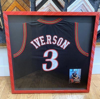 Signed Basketball Jersey - The assignment was to frame a signed Iverson jersey. Our designer collaborated with the client and decided on a flashy red lacquered frame with a black mat. We think the result is quite dynamic. Signed Basketball Jersey - The assignment was to frame a signed Iverson jersey. Our designer collaborated with the client and decided on a flashy red lacquered frame with a black mat. We think the result is quite dynamic.