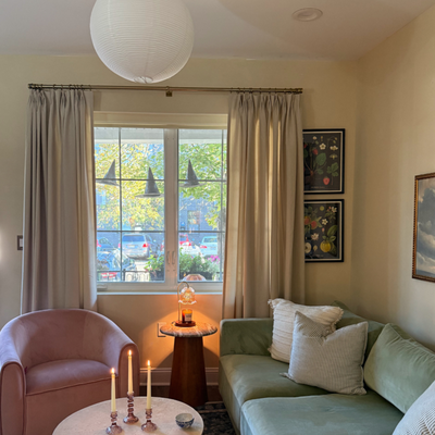 Cozy Minimalist Living Room with Layered Window Treatments - "We set out to create a layered, cozy, and elevated living room look for this townhouse in downtown Philadelphia. This space pairs classic Tailored Pleat Drapery panels in Jefferson White Sand with a sleek light-filtering Roller Shade in Cameo Natural, offering the perfect balance of softness and light control. The window is framed by a timeless brass curtain rod, and the full-length drapes pool gently to the floor, enhancing the room’s elegance and sense of height. A soft Roman Shade in The Latte, color Studio Clay adds dimension and texture. This living space is a beautiful example of how thoughtful details and layered textures can transform a room into a peaceful retreat. The soft ivory drapery provides warmth and volume, while the roller shade adds clean lines and practicality—ideal for managing privacy and natural light without compromising style.The room's palette is rich yet gentle, featuring a sage green velvet sectional, a blush pink accent chair, and neutral, textured throw pillows. A mix of materials—like the sculptural marble coffee table, wood and stone side table, and soft, ambient candlelight—adds depth and comfort.This design is perfect for anyone looking to elevate their home with layered window treatments that combine beauty and function. Whether you’re redecorating a reading nook, designing a cozy lounge, or styling a chic urban apartment, this look proves that neutral tones, soft textures, and quality window coverings can redefine your space.Key Features:Floor-length ivory pinch pleat drapesBrass curtain rod for a classic finishLight-filtering roller shade behind drapery for privacy and brightness controlVelvet green sectional + blush accent chairSoft candlelight and cozy textures for ambiancePerfect for transitional, modern traditional, or cozy minimalist interiors" Cozy Minimalist Living Room with Layered Window Treatments - "We set out to create a layered, cozy, and elevated living room look for this townhouse in downtown Philadelphia. This space pairs classic Tailored Pleat Drapery panels in Jefferson White Sand with a sleek light-filtering Roller Shade in Cameo Natural, offering the perfect balance of softness and light control. The window is framed by a timeless brass curtain rod, and the full-length drapes pool gently to the floor, enhancing the room’s elegance and sense of height. A soft Roman Shade in The Latte, color Studio Clay adds dimension and texture. This living space is a beautiful example of how thoughtful details and layered textures can transform a room into a peaceful retreat. The soft ivory drapery provides warmth and volume, while the roller shade adds clean lines and practicality—ideal for managing privacy and natural light without compromising style.The room's palette is rich yet gentle, featuring a sage green velvet sectional, a blush pink accent chair, and neutral, textured throw pillows. A mix of materials—like the sculptural marble coffee table, wood and stone side table, and soft, ambient candlelight—adds depth and comfort.This design is perfect for anyone looking to elevate their home with layered window treatments that combine beauty and function. Whether you’re redecorating a reading nook, designing a cozy lounge, or styling a chic urban apartment, this look proves that neutral tones, soft textures, and quality window coverings can redefine your space.Key Features:Floor-length ivory pinch pleat drapesBrass curtain rod for a classic finishLight-filtering roller shade behind drapery for privacy and brightness controlVelvet green sectional + blush accent chairSoft candlelight and cozy textures for ambiancePerfect for transitional, modern traditional, or cozy minimalist interiors"