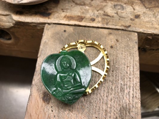 18K yellow gold framing - A customer brought in this beautiful buddha Jade that needed framing. We reviewed several different designs and decided on this design with a heart shape and pitched sides. It took Yan, our goldsmith 2 weeks to complete. 18K yellow gold framing - A customer brought in this beautiful buddha Jade that needed framing. We reviewed several different designs and decided on this design with a heart shape and pitched sides. It took Yan, our goldsmith 2 weeks to complete.
