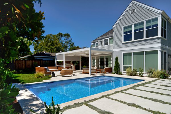 Contemporary Poolside Backyard - This backyard received a complete overhaul. Highlights of the design are the glass mosaic pool, the louvered pergola, the curvy outdoor fire table, and the limestone patio. The front yard has a new stone driveway and low-maintenance plantings for added curb appeal.