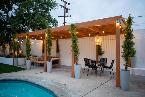 Pergola, Driveway, & Landscape Redesign - This redesign began with a reconstruction of the driveway, using a mix of large concrete pavers in a unique design with grass edging to provide a modern appeal. The backyard project included building an attached pergola, resigning the landscaping, and adding outdoor lighting. This sleek, charming design provides the homeowners with plenty of space to relax and play with minimal maintenance.