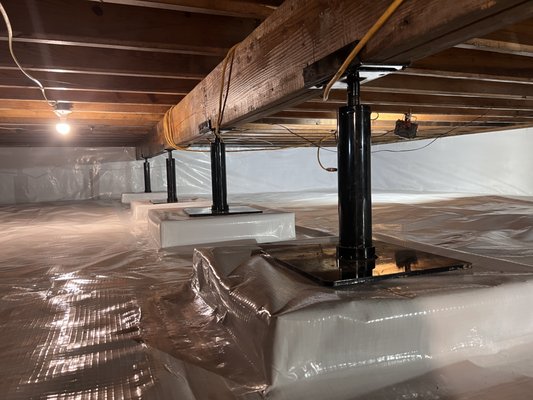 Crawl Space Stabilized with New Support Columns - This crawl space was reinforced with professionally installed steel support columns to stabilize the floor above and prevent further settling. The space was also sealed with a clean vapor barrier, creating a drier, more structurally sound environment for the home.