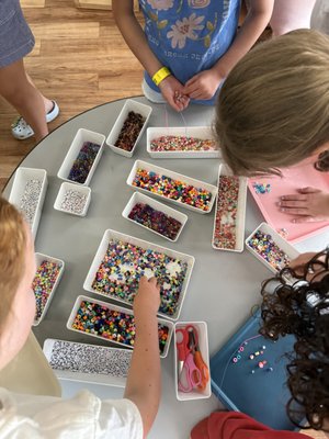 Moonshadow's Bead Parties To-Go - Create a fun, hands-on bead experience without the stress of planning or shopping. Our To-Go Bead Parties includes everything you need for a colorful bead table delivered to your home, school, camp, or event.
Guests can choose from a variety of beads, colors, and charms to create their own bracelets, keychains, and keepsakes at their own pace. Perfect for birthdays, tween parties, camps, childcare programs, and community events, this creative activity is fun for all ages and requires no prep from you.
We bring the beads, supplies, and inspiration. You bring the creativity. Moonshadow's Bead Parties To-Go - Create a fun, hands-on bead experience without the stress of planning or shopping. Our To-Go Bead Parties includes everything you need for a colorful bead table delivered to your home, school, camp, or event.
Guests can choose from a variety of beads, colors, and charms to create their own bracelets, keychains, and keepsakes at their own pace. Perfect for birthdays, tween parties, camps, childcare programs, and community events, this creative activity is fun for all ages and requires no prep from you.
We bring the beads, supplies, and inspiration. You bring the creativity.