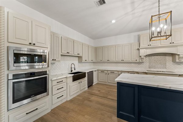 Kitchen Remodel - Cleveland TX - We recently completed a stunning kitchen remodel in Cleveland, TX, transforming the space into a bright, open, and functional area that blends classic elegance with modern convenience. The homeowners wanted a fresh, timeless design with high-end finishes and improved functionality, and we delivered a space that exceeded their expectations.
The remodel included custom shaker-style cabinetry in a soft off-white tone, featuring detailed molding, soft-close doors, and black hardware for a subtle contrast. The centerpiece of the kitchen is a large navy-blue island, providing additional storage, workspace, and a welcoming area for gathering. To complement the cabinetry, we installed marble-look quartz countertops that offer both durability and a high-end aesthetic. The herringbone tile backsplash adds texture and an extra touch of sophistication.
Lighting played a key role in enhancing the overall ambiance. We installed recessed lighting for consistent brightness throughout the space, while gold geometric pendant fixtures over the island add a warm and stylish focal point. The farmhouse sink, finished in sleek matte black, brings a modern yet timeless touch, paired with a black pull-down faucet for added functionality.
Premium built-in stainless steel appliances were incorporated into the design, including a wall oven, microwave, and dishwasher. A custom range hood seamlessly blends into the cabinetry, creating a clean and polished look. The flooring was refinished with wide-plank hardwood, which flows throughout the open-concept living space, making the kitchen feel even more expansive.
By reworking the layout and carefully selecting each finish, this kitchen now feels both inviting and practical. The homeowners were thrilled with the transformation, and the space is now perfect for cooking, entertaining, and everyday living. This remodel was all about combining beauty with functionality, and the results speak for themselves. Kitchen Remodel - Cleveland TX - We recently completed a stunning kitchen remodel in Cleveland, TX, transforming the space into a bright, open, and functional area that blends classic elegance with modern convenience. The homeowners wanted a fresh, timeless design with high-end finishes and improved functionality, and we delivered a space that exceeded their expectations.
The remodel included custom shaker-style cabinetry in a soft off-white tone, featuring detailed molding, soft-close doors, and black hardware for a subtle contrast. The centerpiece of the kitchen is a large navy-blue island, providing additional storage, workspace, and a welcoming area for gathering. To complement the cabinetry, we installed marble-look quartz countertops that offer both durability and a high-end aesthetic. The herringbone tile backsplash adds texture and an extra touch of sophistication.
Lighting played a key role in enhancing the overall ambiance. We installed recessed lighting for consistent brightness throughout the space, while gold geometric pendant fixtures over the island add a warm and stylish focal point. The farmhouse sink, finished in sleek matte black, brings a modern yet timeless touch, paired with a black pull-down faucet for added functionality.
Premium built-in stainless steel appliances were incorporated into the design, including a wall oven, microwave, and dishwasher. A custom range hood seamlessly blends into the cabinetry, creating a clean and polished look. The flooring was refinished with wide-plank hardwood, which flows throughout the open-concept living space, making the kitchen feel even more expansive.
By reworking the layout and carefully selecting each finish, this kitchen now feels both inviting and practical. The homeowners were thrilled with the transformation, and the space is now perfect for cooking, entertaining, and everyday living. This remodel was all about combining beauty with functionality, and the results speak for themselves.