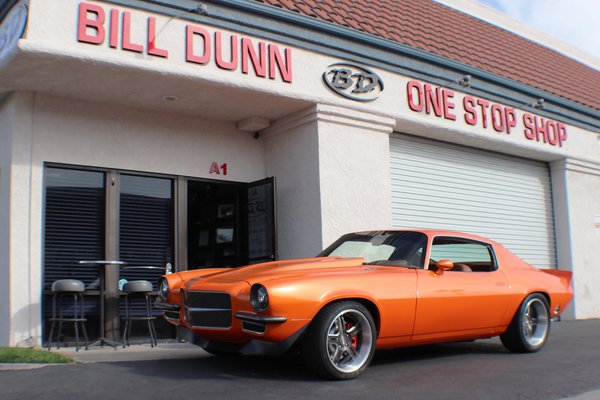 1971 Chevy Camaro - Our 1971 Chevy "SUMMUT" Camaro was built in 2017 for the SEMA show. Built all in house, here in Huntington Beach CA! The car features over 20 different sponsors from some of the industries most reputable companies like Magnaflow Exhaust, Classic Industries, Toyo Tires, American Legend Wheels, Dakota Digital, and MORE!
The car was built with one goal in mind, to have a new & modern look/feel while still driving a classic 1971 vehicle! With that in mind we start with the interior. How much more modern can a 1971 Camaro get than custom fitting almost an entire interior from a 2015 Camaro, over 4 decades of modernization! Over 200 man hours on the interior alone, customizing, fitting, welding, stitching you name it.
Our interior features custom leather seats and door panels designed here in-house at Bill Dunn One Stop Shop. Italian leather throughout the entire car and with a color scheme chosen by the one and only Chip Foose. Thats right tha legend Chip Foose chose the colors that we used throughout the entire interior, from the leather, to the basketweave inserts!
The exterior features a House of Kolor paint names "Tangelo Orange" with an added pearl to really catch any and all wandering eyes! Custom made American Legend Wheels, Magnaflow Exhaust cut outs on the rear panels of the car (either side), Fesler Built flush mount glass to give our windshield a seamless look, Custom front and rear ends ALL built by us here at Bill Dunn One Stop Shop! 1971 Chevy Camaro - Our 1971 Chevy "SUMMUT" Camaro was built in 2017 for the SEMA show. Built all in house, here in Huntington Beach CA! The car features over 20 different sponsors from some of the industries most reputable companies like Magnaflow Exhaust, Classic Industries, Toyo Tires, American Legend Wheels, Dakota Digital, and MORE!
The car was built with one goal in mind, to have a new & modern look/feel while still driving a classic 1971 vehicle! With that in mind we start with the interior. How much more modern can a 1971 Camaro get than custom fitting almost an entire interior from a 2015 Camaro, over 4 decades of modernization! Over 200 man hours on the interior alone, customizing, fitting, welding, stitching you name it.
Our interior features custom leather seats and door panels designed here in-house at Bill Dunn One Stop Shop. Italian leather throughout the entire car and with a color scheme chosen by the one and only Chip Foose. Thats right tha legend Chip Foose chose the colors that we used throughout the entire interior, from the leather, to the basketweave inserts!
The exterior features a House of Kolor paint names "Tangelo Orange" with an added pearl to really catch any and all wandering eyes! Custom made American Legend Wheels, Magnaflow Exhaust cut outs on the rear panels of the car (either side), Fesler Built flush mount glass to give our windshield a seamless look, Custom front and rear ends ALL built by us here at Bill Dunn One Stop Shop!