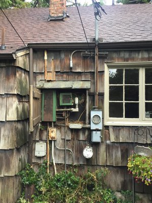 Replace existing outdoor fusebox with new outdoor panel. - Customer had an indoor rated fuse box installed on the exterior of the home, with a small roof framed over to keep the weather out. It was very rusted and in disrepair and desperate need of upgrading. Customer elected to keep the original meter equipment and rusty service pipe on the right, despite our recommendations to update, to keep the project within budget. The existing metering equipment was still in safe operating condition, but due to age and surface rust replacement was recommended. Regardless of the old equipment remaining in place, this was still quite an upgrade from the existing installation and should serve the customer well. Replace existing outdoor fusebox with new outdoor panel. - Customer had an indoor rated fuse box installed on the exterior of the home, with a small roof framed over to keep the weather out. It was very rusted and in disrepair and desperate need of upgrading. Customer elected to keep the original meter equipment and rusty service pipe on the right, despite our recommendations to update, to keep the project within budget. The existing metering equipment was still in safe operating condition, but due to age and surface rust replacement was recommended. Regardless of the old equipment remaining in place, this was still quite an upgrade from the existing installation and should serve the customer well.