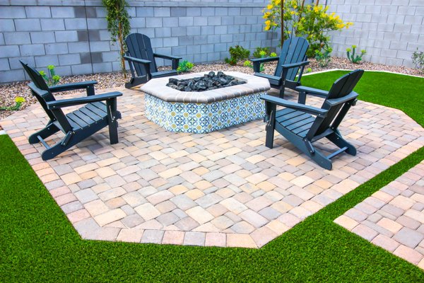 Backyard Paver Patio - The backyard got a makeover featuring paver stone design, a fire pit area, artificial turf, plants, and decorative rock. Backyard Paver Patio - The backyard got a makeover featuring paver stone design, a fire pit area, artificial turf, plants, and decorative rock.