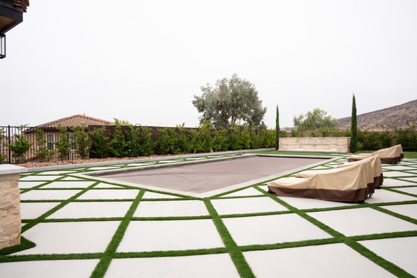 Modern Backyard Oasis with Paver Design, Outdoor Kitchen & Pool – San Diego - This custom backyard remodel in San Diego brings luxury outdoor living to life with clean modern design and high-end features. The space is anchored by a bold geometric paver layout — square concrete slabs separated by crisp green turf lines for a fresh, structured look.
The centerpiece is a large tarped pool, surrounded by multiple zones for entertainment and relaxation. A fully built-out BBQ area with a peach-toned structure includes a fireplace, TV wall, and spacious seating area — perfect for gatherings. Nearby, a modern fire pit with additional seating creates a cozy nighttime hangout, and an outdoor shower adds style and convenience for poolside living. Modern Backyard Oasis with Paver Design, Outdoor Kitchen & Pool – San Diego - This custom backyard remodel in San Diego brings luxury outdoor living to life with clean modern design and high-end features. The space is anchored by a bold geometric paver layout — square concrete slabs separated by crisp green turf lines for a fresh, structured look.
The centerpiece is a large tarped pool, surrounded by multiple zones for entertainment and relaxation. A fully built-out BBQ area with a peach-toned structure includes a fireplace, TV wall, and spacious seating area — perfect for gatherings. Nearby, a modern fire pit with additional seating creates a cozy nighttime hangout, and an outdoor shower adds style and convenience for poolside living.
