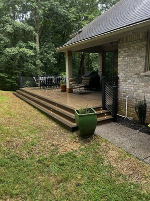 Custom Trex deck construction 2024 - This old deck was completely torn out and rebuilt to be larger, more modern, and more open. The old deck was sagging and unstable due to improper construction so the first thing we did was make sure to give the new deck a solid foundation so it didn't happen again. We graded the area, installed all new concrete footings, and extended the deck by 8 feet to give our clients more space. The high-quality Trex composite decking not only looks beautiful but also ensures that this deck lasts a lifetime with little maintenance required. The cable railing gives a beautiful modern look that provides protection while also leaving an unobscured view of the surrounding yard.
