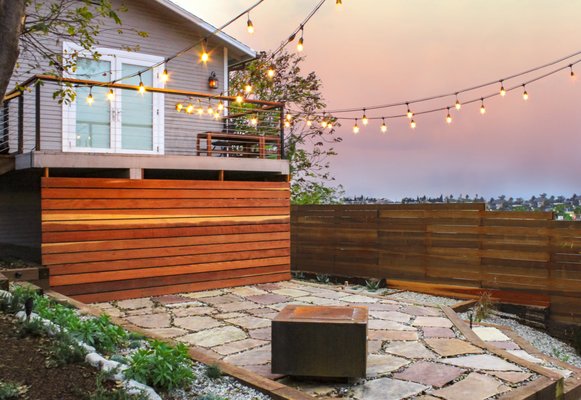 Echo Park Bungalow - At this adorable bungalow home we installed smooth horizontal redwood fencing around the yard and under the balcony. Though not featured in the photos, we also installed a custom steel gate with a numerical "keyless" deadbolt. We installed charming String Edison Light Bulbs in the backyard above Arizona Flagstone pavers and 3/8 inch pea gravel. We were especially proud of the custom fire pit we put in under the Edison Lights. 

As for the side yard, we planted a row of Aloes surrounded by pressure-treated redwood planters. The walkway was made of 2x2 pre-poured concrete pavers and 3/8 inch pea gravel. Of course, as is our custom, we installed drought-conscious drip irrigation for all plants we installed. 

This was one of our favorite projects of 2018 and we're glad to have it our portfolio because of how beautiful it turned out!