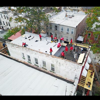 Flat Roof Replacement, Brooklyn NY - This customer's house was built in the early 1900s. For over 100 years, roofers just added another layer on top of the old layer. The customer wanted to do the roof job right this time. And so they hired us to do a full tearoff of the old roof and install a new roof, which would now be in compliance with NY Housing Code's 2 roof layer maximum. With a nearly 30-worker crew, we tore off the old roofs and installed a new white roof in just 1 day! Our company specializes in 1 day roof replacements, and we have the large crew size and sufficient management to nearly always make it happen. And we did it here as usual in 1-day! No leaks ever since! Flat Roof Replacement, Brooklyn NY - This customer's house was built in the early 1900s. For over 100 years, roofers just added another layer on top of the old layer. The customer wanted to do the roof job right this time. And so they hired us to do a full tearoff of the old roof and install a new roof, which would now be in compliance with NY Housing Code's 2 roof layer maximum. With a nearly 30-worker crew, we tore off the old roofs and installed a new white roof in just 1 day! Our company specializes in 1 day roof replacements, and we have the large crew size and sufficient management to nearly always make it happen. And we did it here as usual in 1-day! No leaks ever since!
