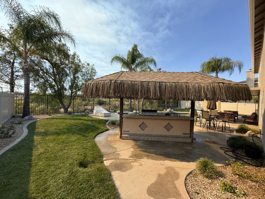 Palapa Roof Replacement- Murrieta, Ca - Our homeowner was tired of replacing her traditional palapa thatch roof every 2 years due to weather and wear. After discussing her options, we recommended converting it to a durable asphalt shingle roofing system. Which offers a 25-35 year lifespan, lower long-term maintenance costs, and our labor warranty included. To preserve the original tropical charm of the patio, we carefully incorporated the existing palapa skirts beneath the new roof throughout the whole perimeter. The result is a beautiful transformation that maintains the original character while providing lasting protection, superior quality, and long term peace of mind.