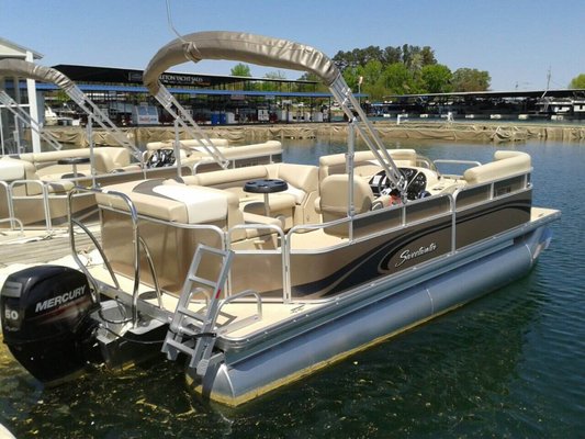 21 Foot Pontoon - Featured as one of our most popular rentals, our 21-foot pontoons are your basic pontoon and just the right size for a small group or family-accommodating 8-9 passengers.
Each boat has couch-style seating and undereating storage for personal items. Designed with a bimini top covering from the captain's seat to the back of the boat, there is plenty of shade on those hot summer days.
This is a value boat ideal for either a 4-hour or 8-hour rental. The ladders on the back allow for easy access to the water for cooling off, splashing around, and jumping on a tube! And most importantly, don’t forget to bring a cooler full of your favorite snacks to complete the perfect day on the lake. 21 Foot Pontoon - Featured as one of our most popular rentals, our 21-foot pontoons are your basic pontoon and just the right size for a small group or family-accommodating 8-9 passengers.
Each boat has couch-style seating and undereating storage for personal items. Designed with a bimini top covering from the captain's seat to the back of the boat, there is plenty of shade on those hot summer days.
This is a value boat ideal for either a 4-hour or 8-hour rental. The ladders on the back allow for easy access to the water for cooling off, splashing around, and jumping on a tube! And most importantly, don’t forget to bring a cooler full of your favorite snacks to complete the perfect day on the lake.