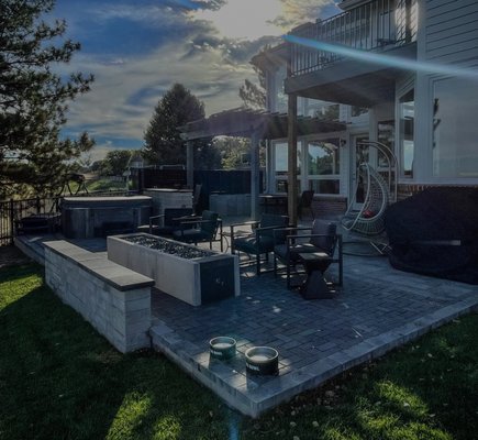 Arvada Project 1 - Engineered outdoor living space featuring a paver patio, custom-formed fireplace, integrated seating wall, outdoor kitchen countertop, pergola, and extended porch. Enhancing property value and lifestyle through expert craftsmanship
