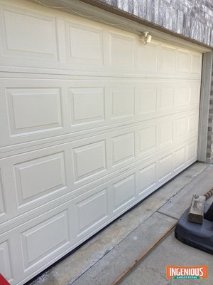 Broken Spring Folded a 16x7 Garage Door in Cypress: New Door Install, August 2026 - The homeowner pressed the remote on the way home, the torsion spring broke, and the top of the door caved in. Steve's inspection found more than the spring. The top two sections were caving in, the bottom two were buckling, several panels had tears, the stiles were separating, the top strut was bent, and the cables were off and damaged.

Fixing it would have meant four new sections plus a spring, cables, rollers and a strut, all bolted to old track. A complete new door cost less than that and will last longer. The old door had also been hand-painted, so new sections would never have matched.

We installed a 16x7 C.H.I. steel door in factory almond with new tracks, hardware, a new spring system, a slide lock and a reinforcement strut. Then we reset the opener's limits, adjusted the trolley and safety sensors, and reprogrammed it. The new door went in four days after the first call.

If your spring breaks, stop pressing the button. The opener will try to lift the whole door by the top section, and that is how a spring job turns into a new door.
