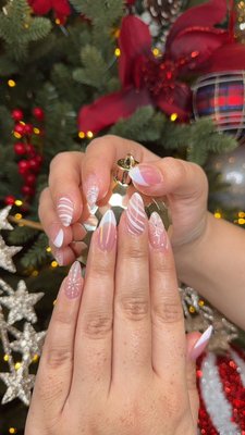 Winter Wonderland Elegance: Delicate Snowflakes & Festive Stripes - This stunning winter-inspired nail set combines elegance and festivity with soft pink and white tones. Featuring delicate hand-painted snowflakes, chic candy cane stripes, and a modern French tip design, these Gel-X nails are perfect for embracing the holiday season. A subtle shimmer adds a touch of magic, making them ideal for any winter celebration! Winter Wonderland Elegance: Delicate Snowflakes & Festive Stripes - This stunning winter-inspired nail set combines elegance and festivity with soft pink and white tones. Featuring delicate hand-painted snowflakes, chic candy cane stripes, and a modern French tip design, these Gel-X nails are perfect for embracing the holiday season. A subtle shimmer adds a touch of magic, making them ideal for any winter celebration!