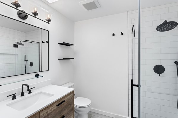 Shower Remodel Kirkland - This complete bathroom remodel transformed two outdated spaces into modern, functional retreats: a full main bathroom and an updated powder room.
In the main bathroom, the dated fiberglass insert shower, old tile-top vanity, builder-grade mirror, lighting, and plumbing fixtures were completely removed. The new main shower features crisp white subway-tiled walls, a built-in shampoo niche, dark hexagonal floor tile, and sleek matte black fixtures with a rain showerhead behind a custom frameless glass enclosure. A warm wood-tone floating vanity with a bright white solid-surface top, matte black plumbing, floating shelves, and updated vanity lighting completed the main bath refresh.
In the powder room, the old black-tiled vanity, drop-in sink, oversized wall mirror, and dated fixture were replaced with a stylish wood-grain vanity, integrated white sink, matte black hardware, a round black-framed accent mirror, and modern globe sconce lighting.
Whether you need a full structural shower overhaul, a complete master bath transformation, or a stylish powder room refresh, our team manages every step from demolition to final detail. Reach out to us today to bring your bathroom vision to life! Shower Remodel Kirkland - This complete bathroom remodel transformed two outdated spaces into modern, functional retreats: a full main bathroom and an updated powder room.
In the main bathroom, the dated fiberglass insert shower, old tile-top vanity, builder-grade mirror, lighting, and plumbing fixtures were completely removed. The new main shower features crisp white subway-tiled walls, a built-in shampoo niche, dark hexagonal floor tile, and sleek matte black fixtures with a rain showerhead behind a custom frameless glass enclosure. A warm wood-tone floating vanity with a bright white solid-surface top, matte black plumbing, floating shelves, and updated vanity lighting completed the main bath refresh.
In the powder room, the old black-tiled vanity, drop-in sink, oversized wall mirror, and dated fixture were replaced with a stylish wood-grain vanity, integrated white sink, matte black hardware, a round black-framed accent mirror, and modern globe sconce lighting.
Whether you need a full structural shower overhaul, a complete master bath transformation, or a stylish powder room refresh, our team manages every step from demolition to final detail. Reach out to us today to bring your bathroom vision to life!