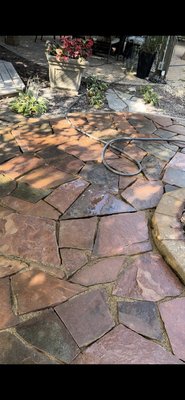 Custom Flagstone Patio & Fireplace Entertainment Circle - Custom-built flagstone patio with a dedicated circular entertainment area designed around a fireplace feature. This project included precise cutting and fitting of natural stone to create a smooth, flowing layout, along with a defined curved border to enhance the fireplace gathering space. The patio was carefully leveled, compacted, and finished with polymeric joint sand for durability and long-term stability. This entertainment circle provides a perfect space for seating, relaxing, and hosting guests while blending naturally with the surrounding landscape.