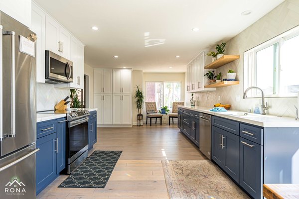 Marina Del Rey Kitchen & Bathroom Transformation - Rona Home Remodeling elevated this Marina Del Rey home with a stunning kitchen and bathroom remodel. For the kitchen, we removed a wall to create an open-concept room addition, seamlessly connecting it to the living area. We installed navy cabinetry with silver handles, white quartz countertops, and a herringbone tile backsplash for a modern look. Stainless steel appliances, including a microwave and gas range, ensure functionality, while floating wooden shelves add warmth. Light oak flooring and large windows create a bright, airy space, perfect for entertaining. The bathroom features a gray vanity with a quartz countertop, a white subway tile shower with black fixtures, and marble hexagon floor tiles. A glass enclosure and rainfall showerhead add luxury, while modern sconces and recessed lighting enhance the serene atmosphere. Marina Del Rey Kitchen & Bathroom Transformation - Rona Home Remodeling elevated this Marina Del Rey home with a stunning kitchen and bathroom remodel. For the kitchen, we removed a wall to create an open-concept room addition, seamlessly connecting it to the living area. We installed navy cabinetry with silver handles, white quartz countertops, and a herringbone tile backsplash for a modern look. Stainless steel appliances, including a microwave and gas range, ensure functionality, while floating wooden shelves add warmth. Light oak flooring and large windows create a bright, airy space, perfect for entertaining. The bathroom features a gray vanity with a quartz countertop, a white subway tile shower with black fixtures, and marble hexagon floor tiles. A glass enclosure and rainfall showerhead add luxury, while modern sconces and recessed lighting enhance the serene atmosphere.