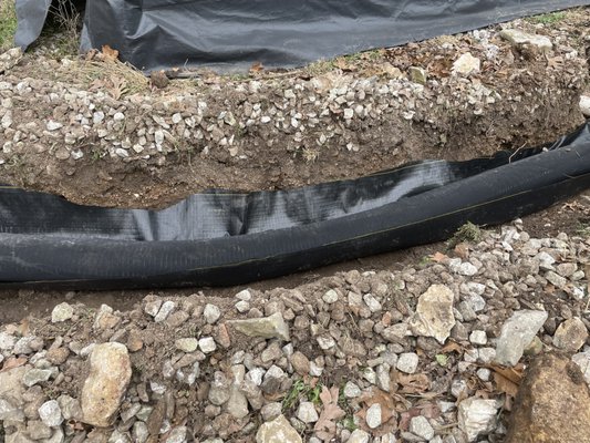 French Drain - This french drain was installed to eliminate pooling of water around the customers driveway and walkway. We used a 6' corrugated pipe with a sock wrap and backfilled with 1-1/2" to 2" limestone rock. In addition, we installed commercial grade ground cover throughout the walkway and covered that with more limestone rock. This gave the customer both functionality and added to the beauty of their property. French Drain - This french drain was installed to eliminate pooling of water around the customers driveway and walkway. We used a 6' corrugated pipe with a sock wrap and backfilled with 1-1/2" to 2" limestone rock. In addition, we installed commercial grade ground cover throughout the walkway and covered that with more limestone rock. This gave the customer both functionality and added to the beauty of their property.