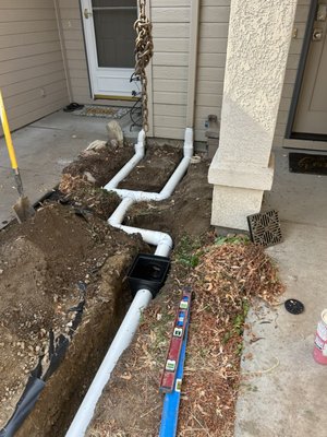 Downspout Drain Routing - This homeowner was dealing with water pooling right next to the house every time it rained. The downspouts were dumping directly at the foundation, which was saturating the soil, washing out the landscaping, and putting the basement/crawlspace at risk of moisture problems.
We routed the downspouts into buried solid drain pipe and carried the water away from the home to a safe discharge point. The pipe was installed with proper slope so water flows freely and doesn't sit in the line, then we backfilled and restored the area so the finished job is clean and nearly invisible.
The result: roof water now leaves the property instead of soaking the soil around the foundation. It's one of the simplest and most affordable ways to protect a home from water damage, settling, and foundation issues down the road. Downspout Drain Routing - This homeowner was dealing with water pooling right next to the house every time it rained. The downspouts were dumping directly at the foundation, which was saturating the soil, washing out the landscaping, and putting the basement/crawlspace at risk of moisture problems.
We routed the downspouts into buried solid drain pipe and carried the water away from the home to a safe discharge point. The pipe was installed with proper slope so water flows freely and doesn't sit in the line, then we backfilled and restored the area so the finished job is clean and nearly invisible.
The result: roof water now leaves the property instead of soaking the soil around the foundation. It's one of the simplest and most affordable ways to protect a home from water damage, settling, and foundation issues down the road.