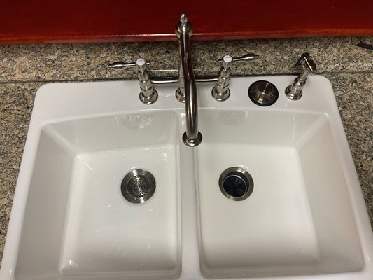 Cast Iron Kitchen Sink - The customer contacted us for a kitchen sink install to replace a less than appealing sink and faucet combo they already had. The customer gave us a little bit of creative free range and asked us to find a pairing that would blend well with the home.

Our take on this was to create a newer look without upsetting the feel of an older home. The last thing we wanted was for them to always have an overly modern sink/faucet that didn't mesh well with the space. We took the challenge and found this beautiful bridge faucet with a perfect brushed nickel color to match the modern stove and fridge will still giving of that vintage feel!!
(We even matched the new drain attachments in color!!)