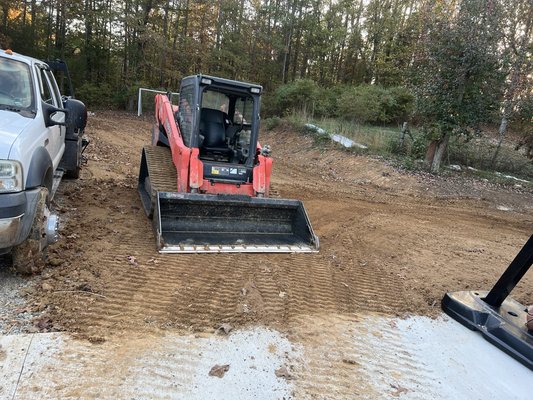 Grading around driveway and around property 2024. - This customer wanted us to add some dirt around their new driveway and put some seed and straw on it. They also had us do some drains to help the water flow away from their house and detached garage.