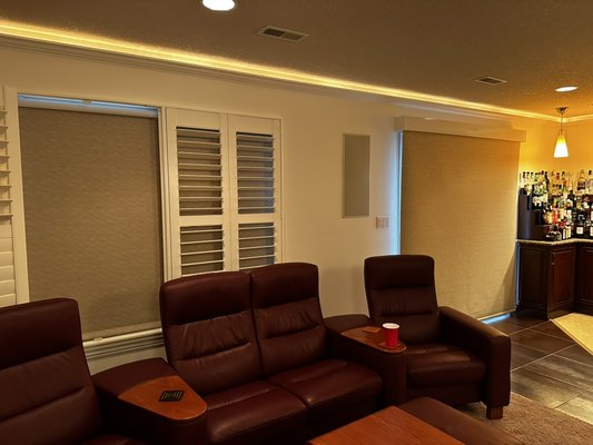 Custom automated blackout blinds. - The customer requested room darkening shades to block out light while enjoying a movie in the basement. The shutters were pre-installed by another company, but we were able to do an inside mount rollup blind and matching blind over the patio door to take away as much light as possible. These blinds can be controlled via remote control and also integrated with the lights, sound system, and also alarm. Custom automated blackout blinds. - The customer requested room darkening shades to block out light while enjoying a movie in the basement. The shutters were pre-installed by another company, but we were able to do an inside mount rollup blind and matching blind over the patio door to take away as much light as possible. These blinds can be controlled via remote control and also integrated with the lights, sound system, and also alarm.