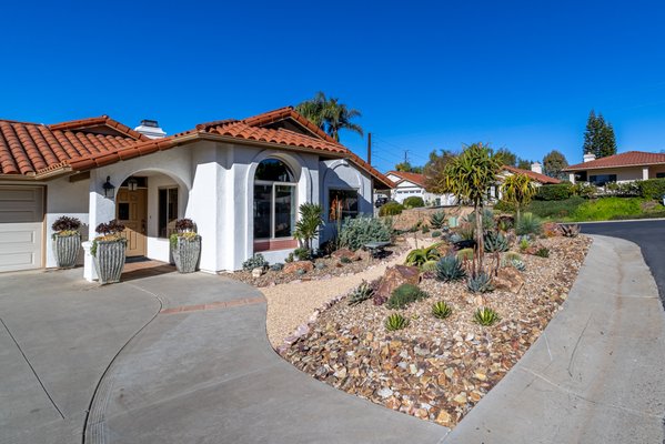Succulent Specimen Garden - This stunning succulent garden showcases a vibrant and thoughtfully designed xeriscape that used to be a water thirsty, traditional lawn. Now, it's a sustainable showpiece featuring a dynamic mix of sculptural succulents, resilient Agaves, and striking Aloes-all thriving in a beautiful mix of decorative gravels and nestled amongst Baja Cresta Red Boulders. Absolutely eye-catching from the street, the pea gravel pathway brings you into the space to be closer to the ever-changing dynamics and details of this incredible garden.