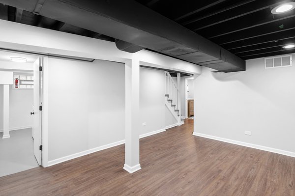 Jefferson Park Finished Basement & Bathroom Remodel - Complete basement build-out in Jefferson Park, Chicago, featuring a modern open-concept main area with exposed painted ceilings, a custom full bathroom with black accents and geometric tile, and a separate laundry room. Jefferson Park Finished Basement & Bathroom Remodel - Complete basement build-out in Jefferson Park, Chicago, featuring a modern open-concept main area with exposed painted ceilings, a custom full bathroom with black accents and geometric tile, and a separate laundry room.