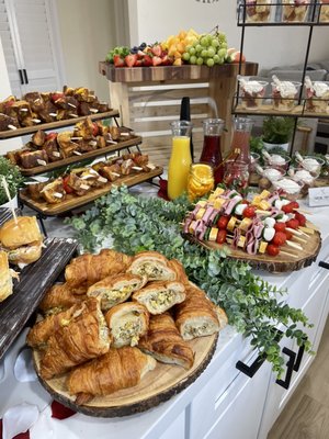 Brunch Catering - Brunch setup with fresh fruit, breakfast croissants, mimosa bar, French toast skewers, charcuterie skewers, Caesar salad cups, and Nashville fried chicken sliders. Brunch Catering - Brunch setup with fresh fruit, breakfast croissants, mimosa bar, French toast skewers, charcuterie skewers, Caesar salad cups, and Nashville fried chicken sliders.