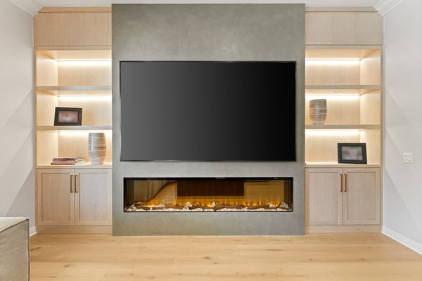 Living Room Addition with Built-In Fireplace and Custom Media Wall by Preferred Home Builders, Calabasas, CA - At Preferred Home Builders in Calabasas, CA, we recently completed a refined living room addition that delivers both modern functionality and custom craftsmanship. This project was designed to transform a simple wall into a sleek, multi-functional focal point, and the result speaks for itself.
We built out a full media wall that integrates a contemporary electric fireplace with a wall-mounted flat-screen TV, all framed within a smooth plaster-finish surround. Flanking the fireplace are custom-built shelving units with warm LED lighting, offering both ambient illumination and space for display. Below the shelves, matching cabinetry provides additional storage while maintaining a seamless aesthetic.
Every element of this design was tailored to fit the homeowner’s lifestyle, from concealed wiring to the clean, floating layout. The electric fireplace adds year-round comfort and a visual centerpiece, while the overall structure anchors the living room with balanced warmth and modern edge.
This kind of transformation is what we specialize in, blending function, form, and high-end finish work to elevate everyday spaces.
If you're in the Calabasas area and considering a custom living room addition, connect with Preferred Home Builders. Living Room Addition with Built-In Fireplace and Custom Media Wall by Preferred Home Builders, Calabasas, CA - At Preferred Home Builders in Calabasas, CA, we recently completed a refined living room addition that delivers both modern functionality and custom craftsmanship. This project was designed to transform a simple wall into a sleek, multi-functional focal point, and the result speaks for itself.
We built out a full media wall that integrates a contemporary electric fireplace with a wall-mounted flat-screen TV, all framed within a smooth plaster-finish surround. Flanking the fireplace are custom-built shelving units with warm LED lighting, offering both ambient illumination and space for display. Below the shelves, matching cabinetry provides additional storage while maintaining a seamless aesthetic.
Every element of this design was tailored to fit the homeowner’s lifestyle, from concealed wiring to the clean, floating layout. The electric fireplace adds year-round comfort and a visual centerpiece, while the overall structure anchors the living room with balanced warmth and modern edge.
This kind of transformation is what we specialize in, blending function, form, and high-end finish work to elevate everyday spaces.
If you're in the Calabasas area and considering a custom living room addition, connect with Preferred Home Builders.