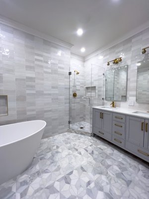 Step into luxury with our latest master bathroom remodel! - We remodeled this bathroom into a sophisticated oasis, blending modern design with classic elegance. Mosaic tiles, sleek grey tones, and accents of gold fixtures create a chic ambiance that's both inviting and luxurious. Featuring a spacious corner shower complete with a convenient shampoo niche, a stunning freestanding bathtub for ultimate relaxation, and a beautiful grey double sink vanity that offers ample storage and style. But that's not all – our design incorporates a thoughtful touch of tradition with separate double mirrors, elegantly lit from above for that perfect glow. Can you spot your favorite detail? Let us know in the comments below! Step into luxury with our latest master bathroom remodel! - We remodeled this bathroom into a sophisticated oasis, blending modern design with classic elegance. Mosaic tiles, sleek grey tones, and accents of gold fixtures create a chic ambiance that's both inviting and luxurious. Featuring a spacious corner shower complete with a convenient shampoo niche, a stunning freestanding bathtub for ultimate relaxation, and a beautiful grey double sink vanity that offers ample storage and style. But that's not all – our design incorporates a thoughtful touch of tradition with separate double mirrors, elegantly lit from above for that perfect glow. Can you spot your favorite detail? Let us know in the comments below!