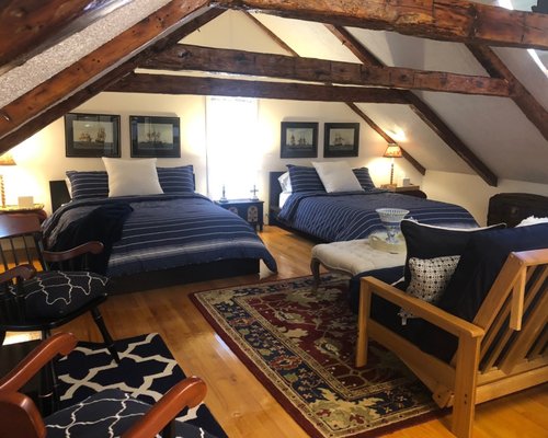 The Marion Suite - Enjoy the beautiful hand-hewn beams and privacy of this large family suite on the entire 3rd floor of the house. There are two queen beds, a sitting area with queen futon, two twin beds, and an ensuite, private bathroom with dual sink vanity, and a combination shower/bath. Please note that the staircase is slightly steeper than normal and the collar tie beams cross the room at 5'7" above the floor. WiFi and a refrigerator are available in all suites!