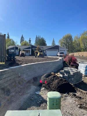Retaining Wall Installation - This project involved the design and installation of a durable retaining wall to stabilize the landscape and create a clean, usable outdoor space. The existing area had a noticeable slope, which was causing soil movement, poor drainage, and limited functionality.

We began by excavating and preparing a solid base, ensuring proper grading and compaction to support the structure long-term. A compacted gravel foundation was installed to provide stability and allow for effective drainage behind the wall. We also integrated a drainage system to prevent water buildup and reduce pressure over time.

The wall was constructed using high-quality materials selected for both strength and appearance, creating a structure that not only performs well but also enhances the overall look of the property. Each block was carefully leveled and aligned to ensure a clean, uniform finish.

Once the wall was in place, we backfilled and compacted the area, restoring the surrounding landscape and leaving the site clean and ready for use.

Result:
A strong, long-lasting retaining wall that prevents erosion, improves drainage, and adds a polished, structured look to the property.
