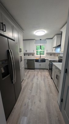 Lilburn Kitchen Remodel - This kitchen was the last original space in a house where we had already updated all the bathrooms and living areas. It was definitely time for a kitchen upgrade!
Our customer chose a stylish two-tone look with dove gray for the base cabinets and pantry, and white shaker cabinets for the uppers. We complemented this with beautiful quartz countertops in a leathered finish, brand-new appliances, and vintage-look subway tile. For easy maintenance, we installed LVP flooring throughout the kitchen.
A cool feature we added was under-cabinet lighting with a motion sensor. And the farmhouse sink is incredibly functional, especially with the slide-in cutting board and wash tray.