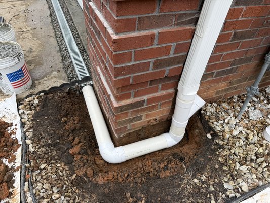 Downspout Drainage System & Garage Channel Drain Installation | Greenville, SC - This homeowner was experiencing water collecting around the garage and foundation due to poor drainage and short downspout discharge.

Our team excavated around the downspout and installed a solid PVC drainage system to carry roof runoff safely away from the home’s foundation. We also installed a channel drain along the garage entrance to intercept surface water before it could enter the garage.