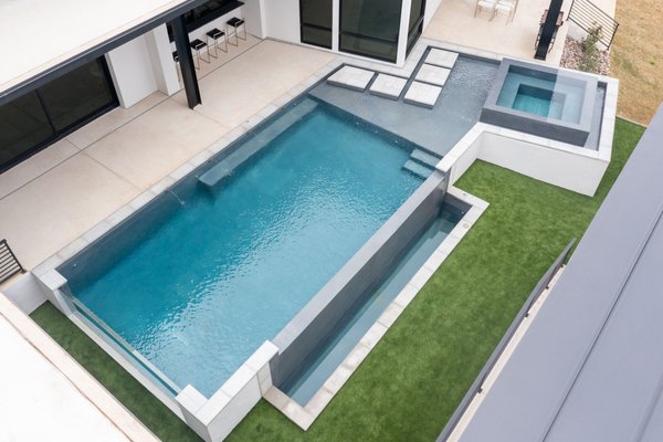 Modern, Acrylic Glass Wall Pool & Spa - Our designer elevated this backyard by crafting a pool that fits perfectly in this unique space!  The customer wanted a modern look to match their residence and Gary Pools delivered a beautiful pool that features an acrylic glass wall, an infinity edge, floating steps, and infinity edge spa, & more!