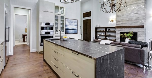 Kitchen Remodel - 2025 - This kitchen featured several dated elements that limited both style and functionality — a small island with minimal storage, older tile countertops, a vintage dark‑stained oven cabinet with an aging built‑in oven/microwave combo, and worn engineered wood flooring. The homeowners wanted a more modern layout with better storage, updated materials, and a cleaner overall look.

We removed the existing island, the built‑in oven cabinet, and the old flooring to prepare the space for a full refresh. A new kitchen island was installed featuring a quartz countertop with a waterfall edge, generous storage on one side, and a bar‑height eating area on the other for added seating. We also installed a new oven/microwave combo in a custom cabinet to replace the outdated built‑in unit. Luxury vinyl flooring was added throughout the kitchen and the adjacent fireplace lounge area, creating a seamless, modern flow between the two spaces.

The result is a brighter, more functional kitchen with a centerpiece island and updated appliances that elevate both everyday use and entertaining.